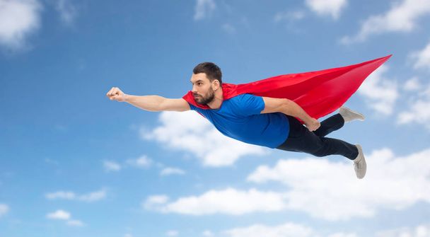 man in red superhero cape flying over blue sky - Foto, immagini