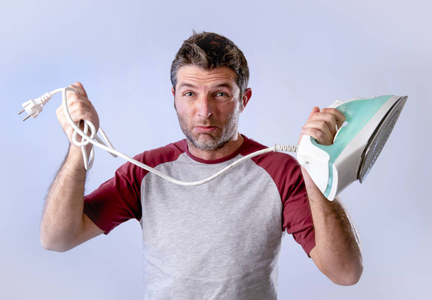young crazy desperate and frustrated man doing housework holding iron - 写真・画像