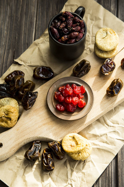 сухофрукты на кухонной доске - финики, инжир и сушеные вишни
 - Фото, изображение