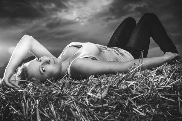 girl lying on haystack stormy sky in the background - Foto, immagini