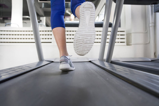 Vrouw voeten op threadmill op sportschool - Foto, afbeelding