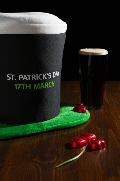 Saint Patrick jour avec une pinte de bière noire, chapeau et trèfle sur une table
 - Photo, image