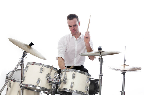 барабанщик за барабанним набором носить білу сорочку і грає на барабанах
 - Фото, зображення