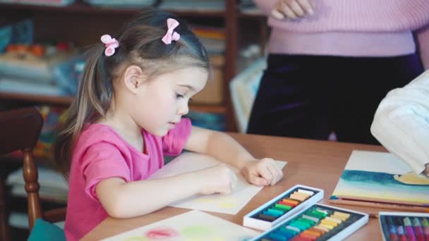 Meisje tekent u met kleurpotloden aan de tafel - Video