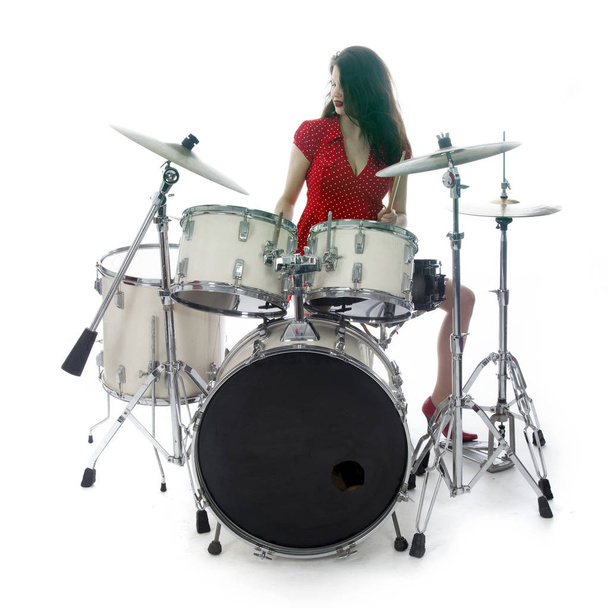 sexy brunette in red dress plays drum kit in studio - Photo, Image