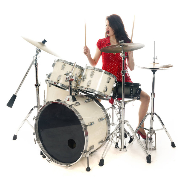 sexy brunette in red dress plays drum kit in studio - Photo, Image