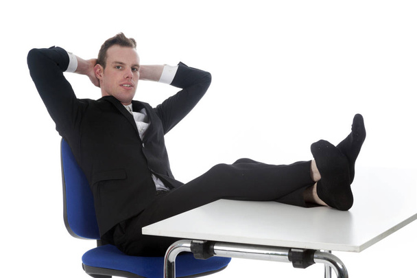 молодой человек сидит на офисном стуле с ногами на столе
 - Фото, изображение