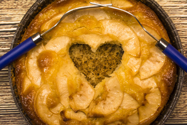 Tarta de manzana con forma de corazón hueco y dos tenedores entrelazados en un
 - Foto, Imagen