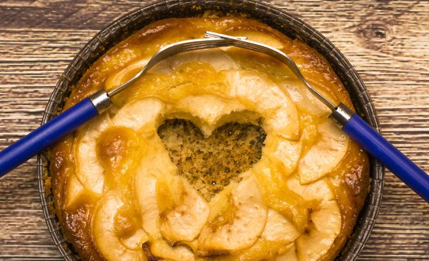 Torta de maçã com um coração oco em forma e dois garfos entrelaçados em um
 - Foto, Imagem