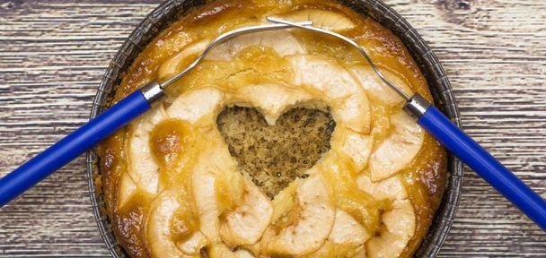 Μηλόπιτα με ένα κοίλο σχήμα καρδιάς και δύο πιρούνια περιπλέκονται σε ένα - Φωτογραφία, εικόνα