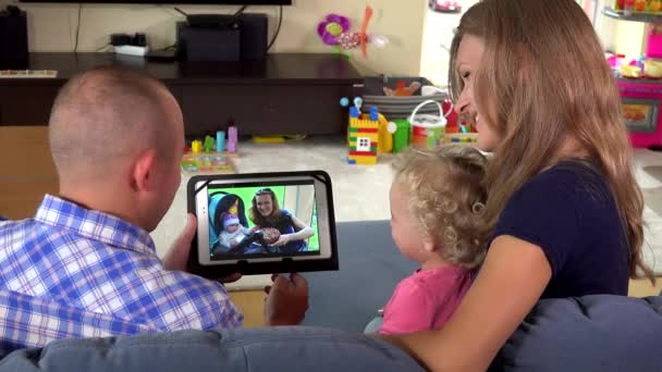 Klein kind met ouders kijken naar foto's album op tablet pc - Video