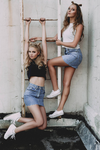 Lifestyle- und People-Konzept: Modeporträt zweier stilvoller Freundinnen in Jeansröcken, draußen auf dem Dach. fröhliche Sommerzeit zum Spaß. Konzept der 90er Jahre. retuschiertes Foto - Foto, Bild