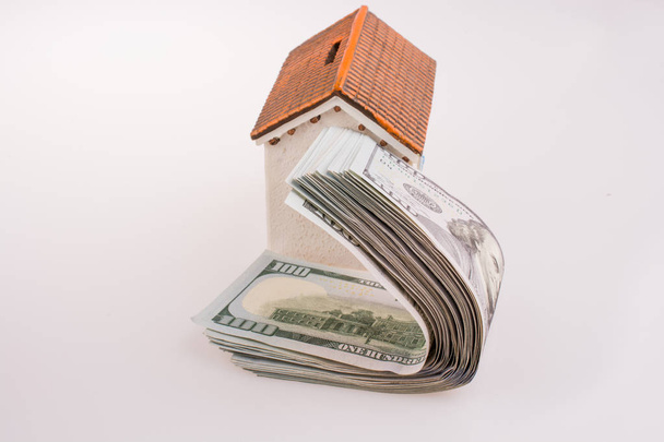 Billetes en dólares americanos en el techo de una casa modelo sobre fondo blanco - Foto, imagen