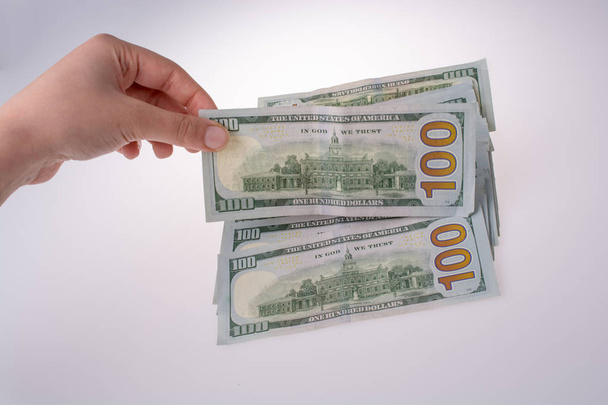 Ihmisellä on hallussaan Amerikan dollarin seteleitä valkoisella pohjalla
 - Valokuva, kuva