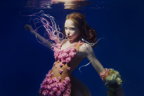 портрет молодой красивой рыжей девушки в розовом платье и с розами под водой
 - Фото, изображение