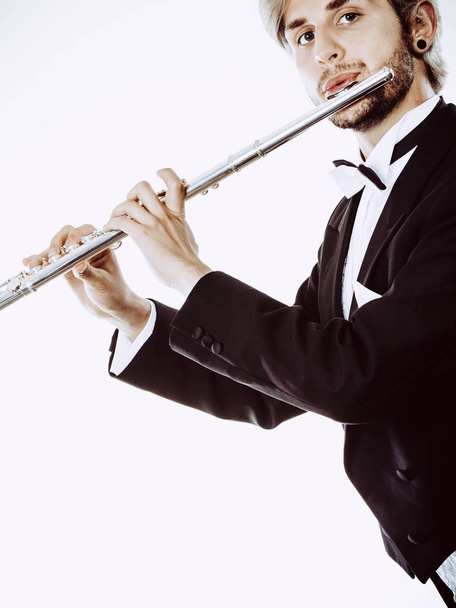 Male flutist wearing tailcoat plays flute - Foto, Bild