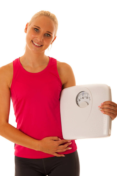Fit blonde woman holding scale gesturing healthy lifestyle and w - Foto, afbeelding