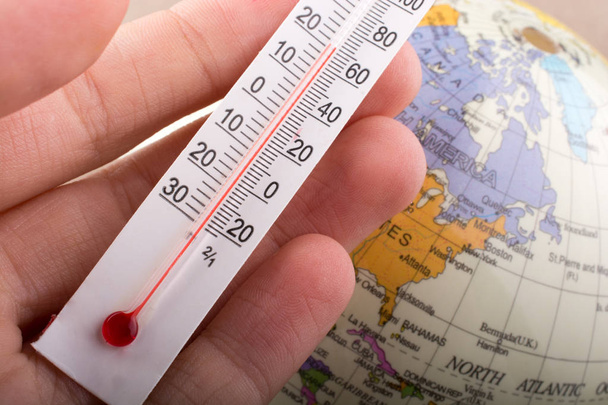 Hand placing a thermometer on a model globe  - Photo, Image