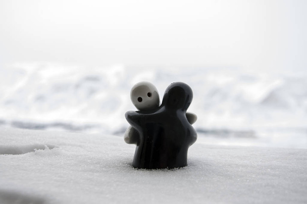 Láska taje ledu je Valentýn koncept. F dívka a chlapec panenky objetí navzájem, stojící na bílém sněhu s rozmazané pozadí. Objímání soch. Suvenýr. Mramorové objekt. Láska. Sympatie - Fotografie, Obrázek