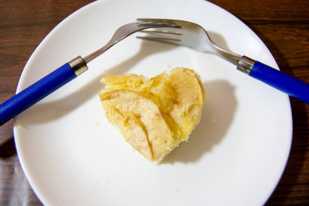 Pedazo de tarta de manzana con forma de corazón y dos tenedores entrelazados
  - Foto, Imagen