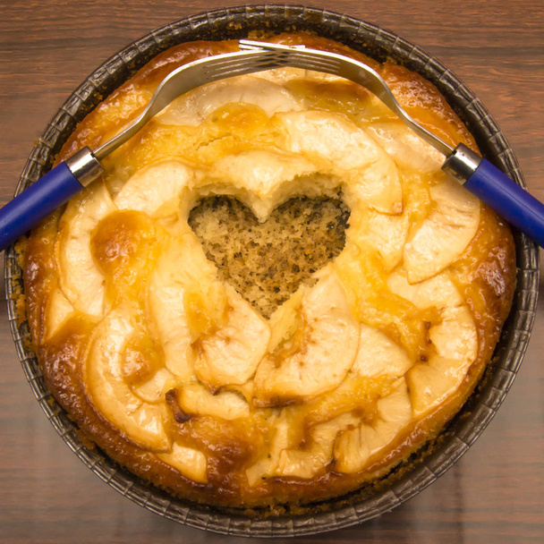 Tarta de manzana con forma de corazón hueco y dos tenedores entrelazados en un
 - Foto, Imagen