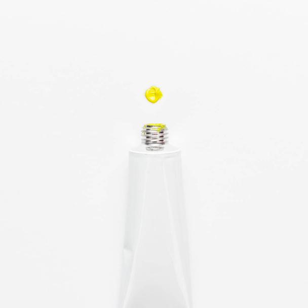 oil paint tube and yellow dot on white background - Foto, imagen