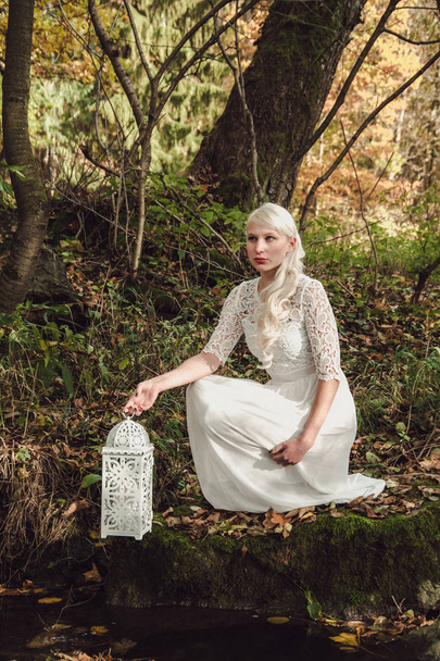 nő fehér ruhában, és a lámpa az erdő - Fotó, kép