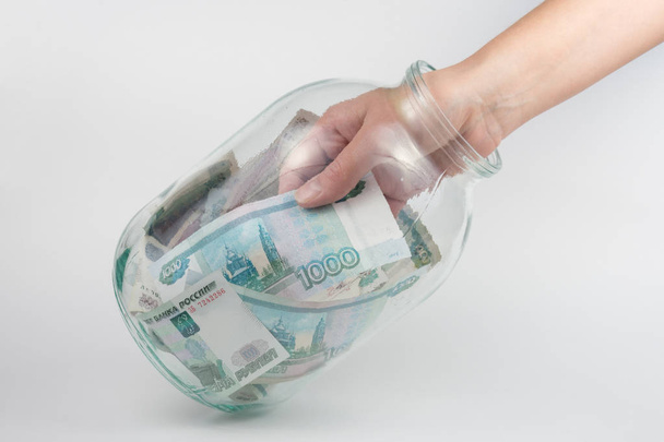 Рука виймає з три літровий скляні банки тисяч російських рублях - Фото, зображення
