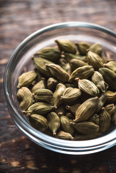 Cardamom seeds in a bowl on a brown board - Foto, immagini