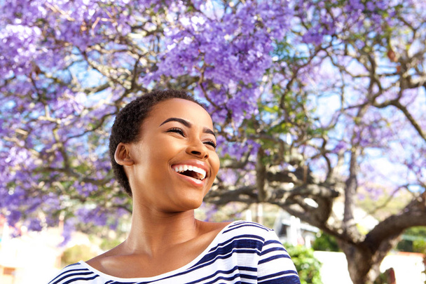 Kobieta, śmiejąc się na zewnątrz przez drzewo kwiat - Zdjęcie, obraz