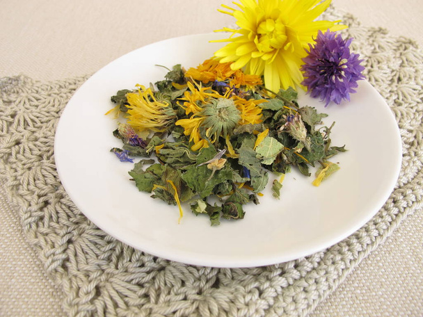 Herbal tea mix with flowers on a small plate - Photo, Image