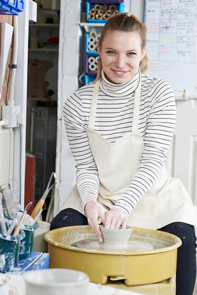 Woman Working At Pottery Wheel In Studio - Foto, afbeelding