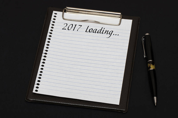 Top view of clipboard and white sheet written with 2017 Loading  - Photo, Image