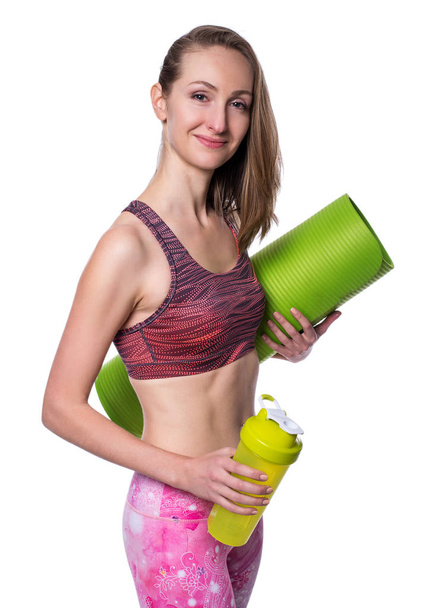 Happy sporty woman with green mat and shaker looking at camera in studio. Isolated on white background. - Foto, immagini