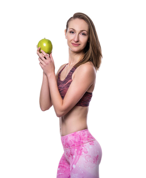 Happy sporty woman with green apple looking at camera in studio. Isolated on white background. - Fotó, kép
