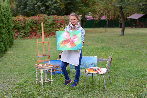 Artist woman holds painting and looks at it, posing at camera an - Photo, Image
