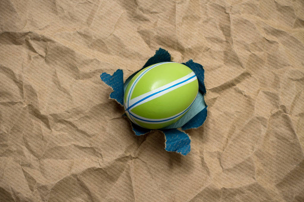 Восточное зеленое яйцо в коричневой оберточной бумаге
 - Фото, изображение