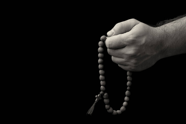 Rosary in male hands on a black background - Zdjęcie, obraz