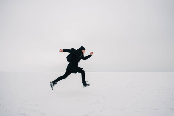 a young man in a black backpack and traveling on the frozen pond - Photo, Image