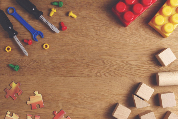 Мальчики игрушки рамка фона. Красочные игрушечные инструменты, строительные блоки и кубики на деревянном столе. Вид сверху. Плоский лежал. Копирование текста
 - Фото, изображение