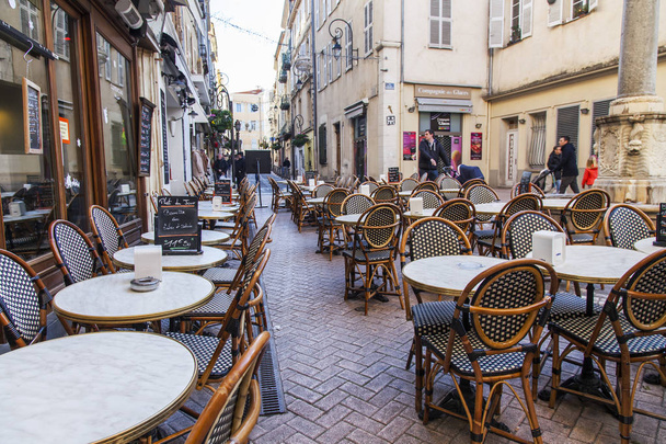 ANTIBES, FRANCE, on JANUARY 6, 2017. The sun lights the city street and little tables of cafe in the morning - Фото, зображення