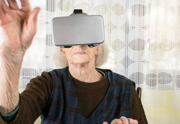 Senior woman using virtual reality goggles - Foto, afbeelding