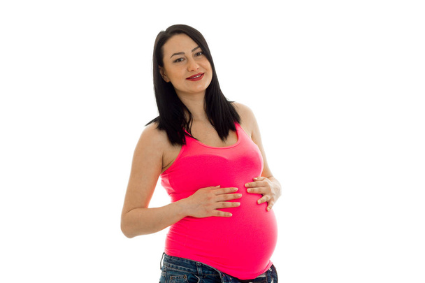 young pregnant brunette woman with big belly posing in pink shirt isolated on white background - Zdjęcie, obraz