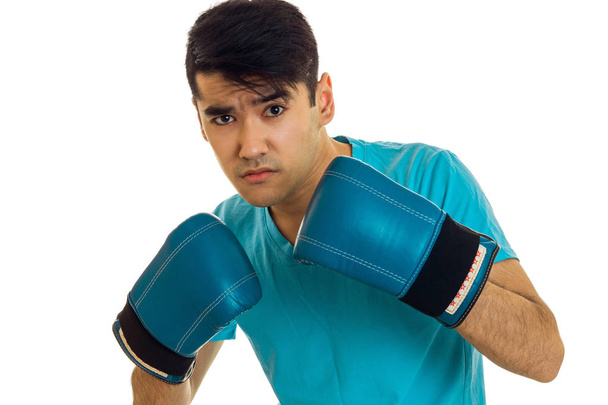 young concentrated man in blue shirt practicing boxing in gloves isolated on white background - Foto, Bild