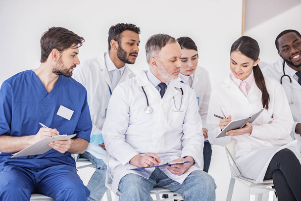 Χαρούμενα γιατρός λέει με τους εταίρους στην κλινική - Φωτογραφία, εικόνα