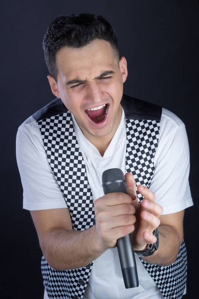 Un chanteur de rock aux cheveux noirs chante au microphone
 - Photo, image
