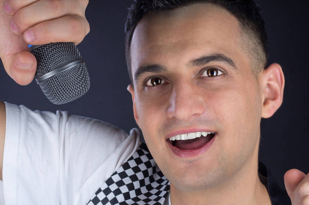 Young male black-haired pop singer performs with microphone - Photo, Image