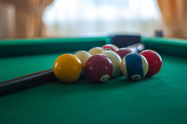 Billiard balls on green table with billiard cue in a hotel hall - Foto, afbeelding
