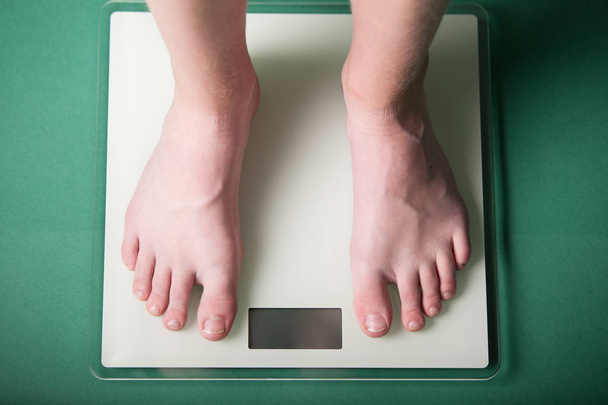 Young boy weighing himself on a scale - Photo, Image