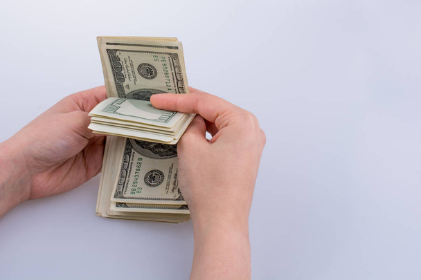 Mão humana segurando notas de dólar americano no fundo branco
 - Foto, Imagem